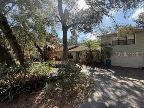 A two-story house with a garage and driveway is surrounded by trees and landscaping — 684 STRATFORD DRIVE, DELAND, FL