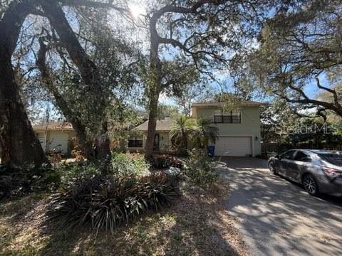 A two-story house with light green siding is surrounded by large trees and a driveway — 684 STRATFORD DRIVE, DELAND, FL