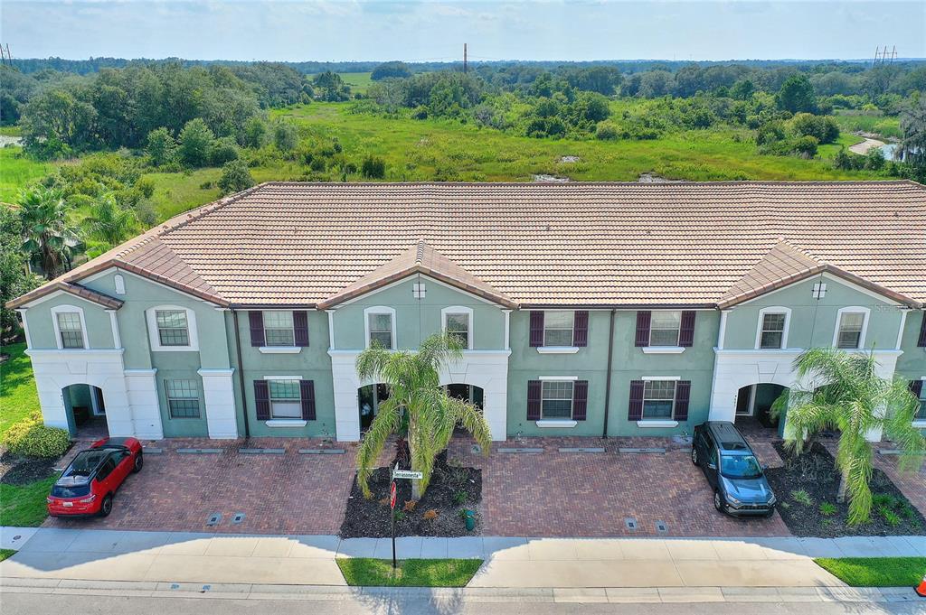 An aerial view of a multi-unit townhouse building with a brick driveway and palm trees — 4607 TERRASONESTA DRIVE, DAVENPORT, FL