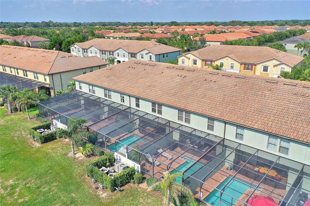 An aerial view of multi-story townhomes with screened-in back patios and private swimming pools — 4607 TERRASONESTA DRIVE, DAVENPORT, FL