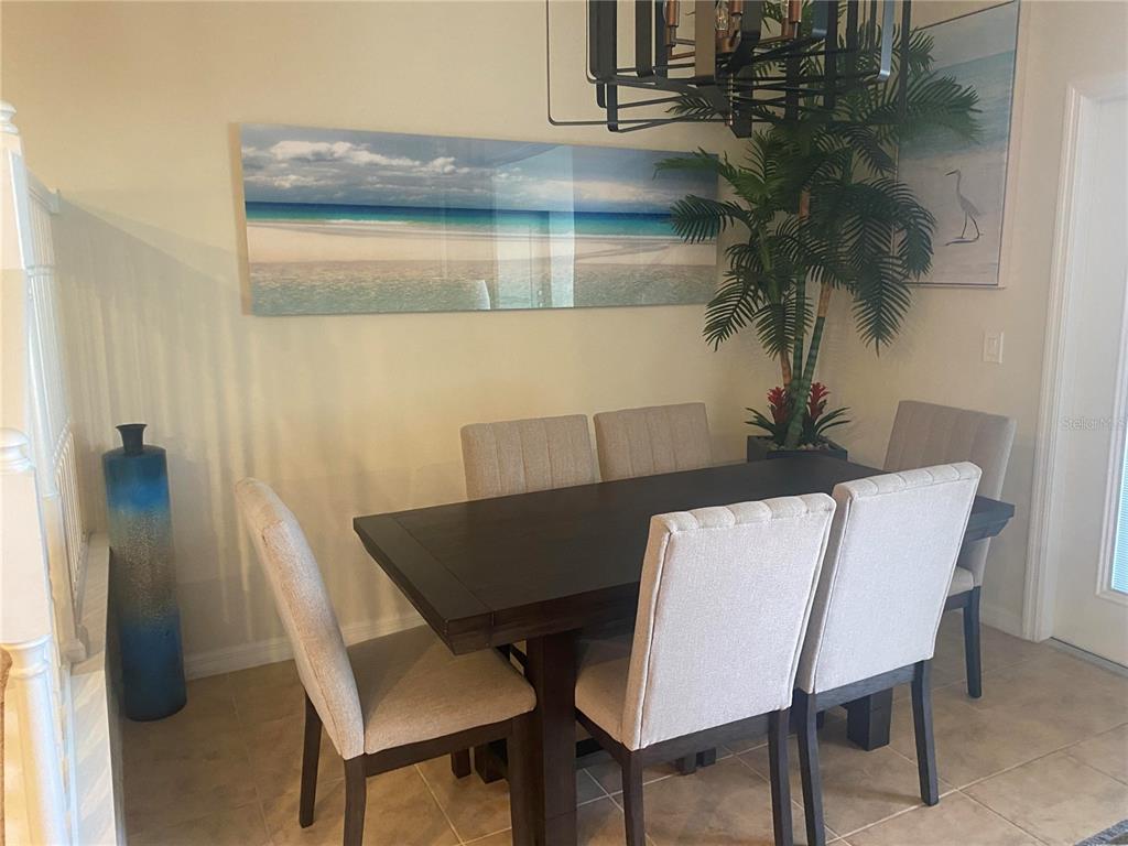A dining room features a dark wood table, six upholstered chairs, and a beach-themed wall print — 4607 TERRASONESTA DRIVE, DAVENPORT, FL