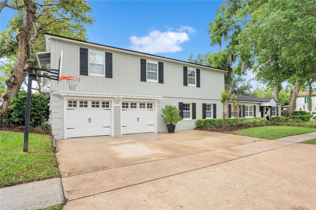 A two-story house with light green siding, a two-car garage, and a basketball hoop — 2702 PARKLAND DRIVE, WINTER PARK, FL