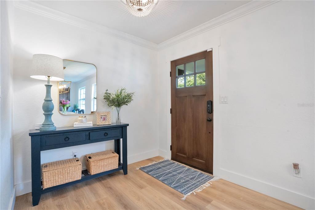 An entryway features a wooden front door, a blue console table, and light wood flooring — 2702 PARKLAND DRIVE, WINTER PARK, FL