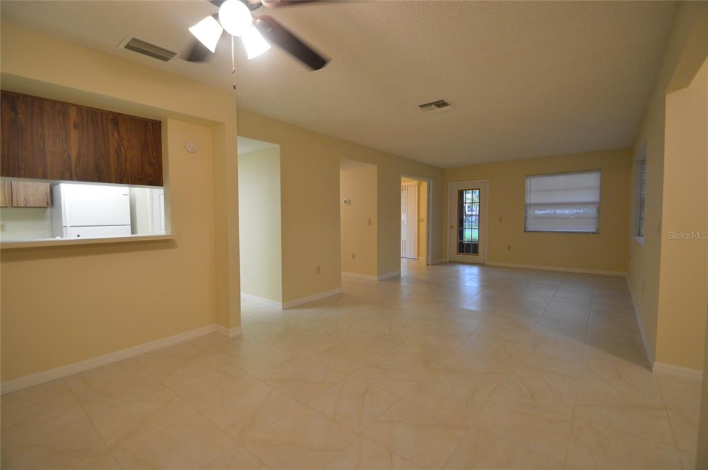 An open-concept living and dining area features light-colored tile flooring and a kitchen pass-through — 12010 PROCTOR LOOP UNIT 4, NEW PORT RICHEY, FL