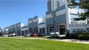A row of modern commercial storefronts with white facades and blue accents under a clear sky — 235 RIVERSIDE DRIVE, DAYTONA BEACH, FL