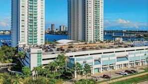 An aerial view shows two high-rise residential towers next to a multi-level parking garage — 235 RIVERSIDE DRIVE, DAYTONA BEACH, FL