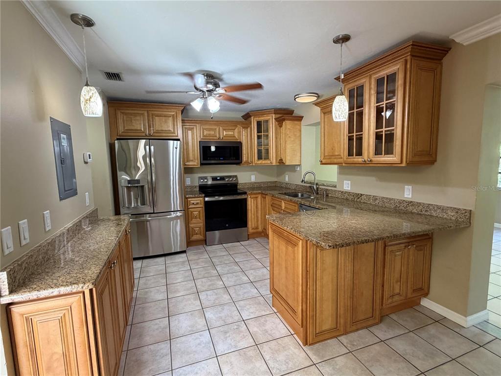 A kitchen features wood cabinets, granite countertops, stainless steel appliances, and tile flooring — 3413 51ST AVENUE CIRCLE W UNIT 205, BRADENTON, FL