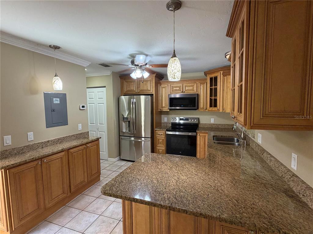 A kitchen features wood cabinets, granite countertops, stainless steel appliances, and tile flooring — 3413 51ST AVENUE CIRCLE W UNIT 205, BRADENTON, FL
