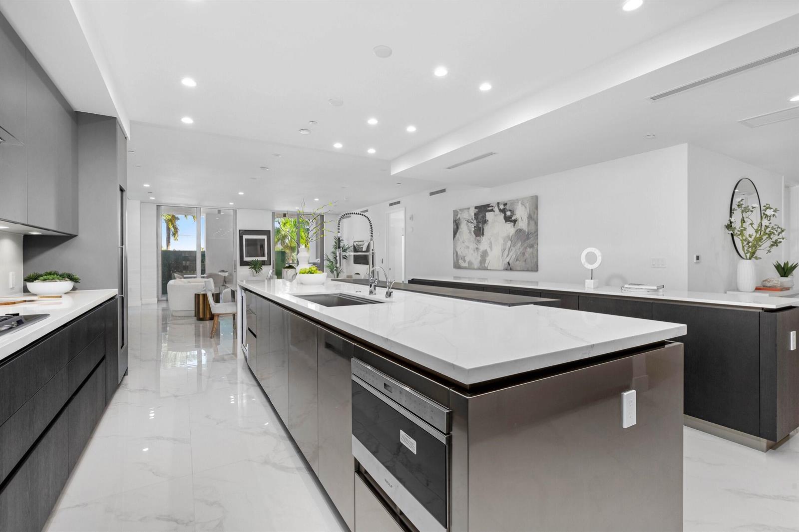 A modern kitchen features a large white marble island, dark cabinetry, and glossy tile floors — 495 E Royal Palm Road # 201, Boca Raton FL 33432, BOCA RATON, FL