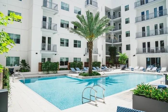 An outdoor swimming pool is surrounded by a multi-story apartment building with balconies and landscaping — 505-3 CHATHAM AVE AVENUE, ORLANDO, FL