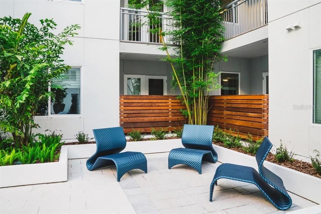 Three blue lounge chairs sit on a paved patio surrounded by planters and wooden fencing — 505-3 CHATHAM AVE AVENUE, ORLANDO, FL