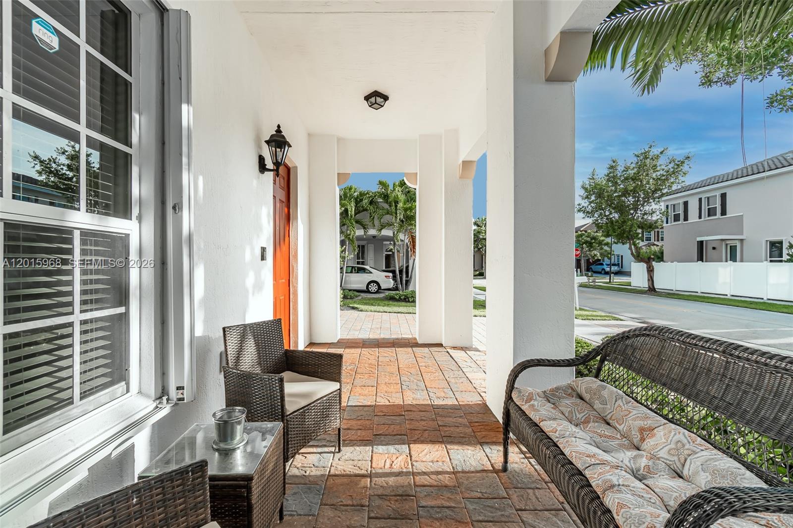 A covered front porch features tiled flooring, wicker furniture, and white support columns — 17046 SW 94th Ln, Miami FL 33196, MIAMI, FL