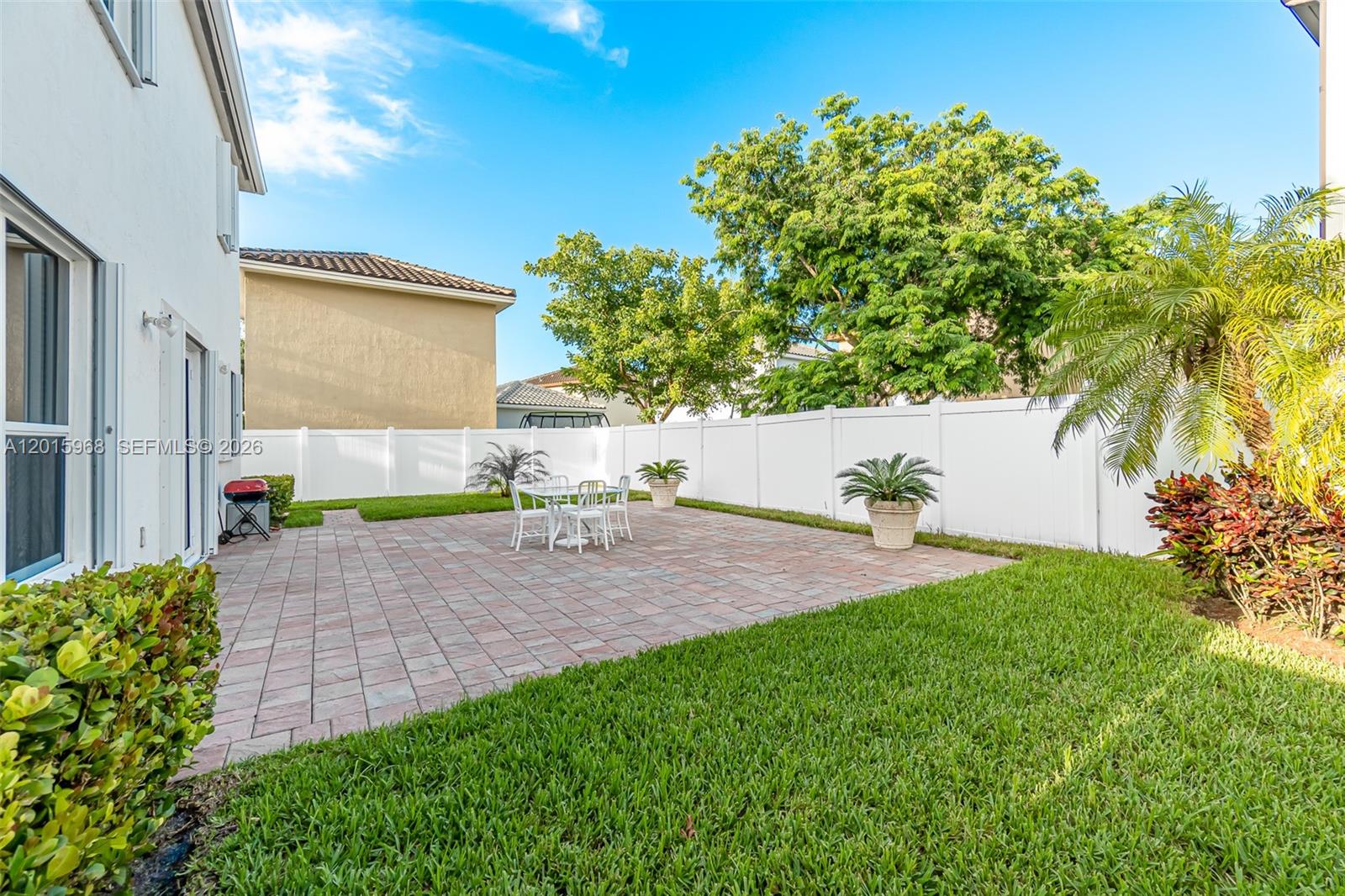 A backyard features a paved patio, a white vinyl fence, and a small dining set — 17046 SW 94th Ln, Miami FL 33196, MIAMI, FL