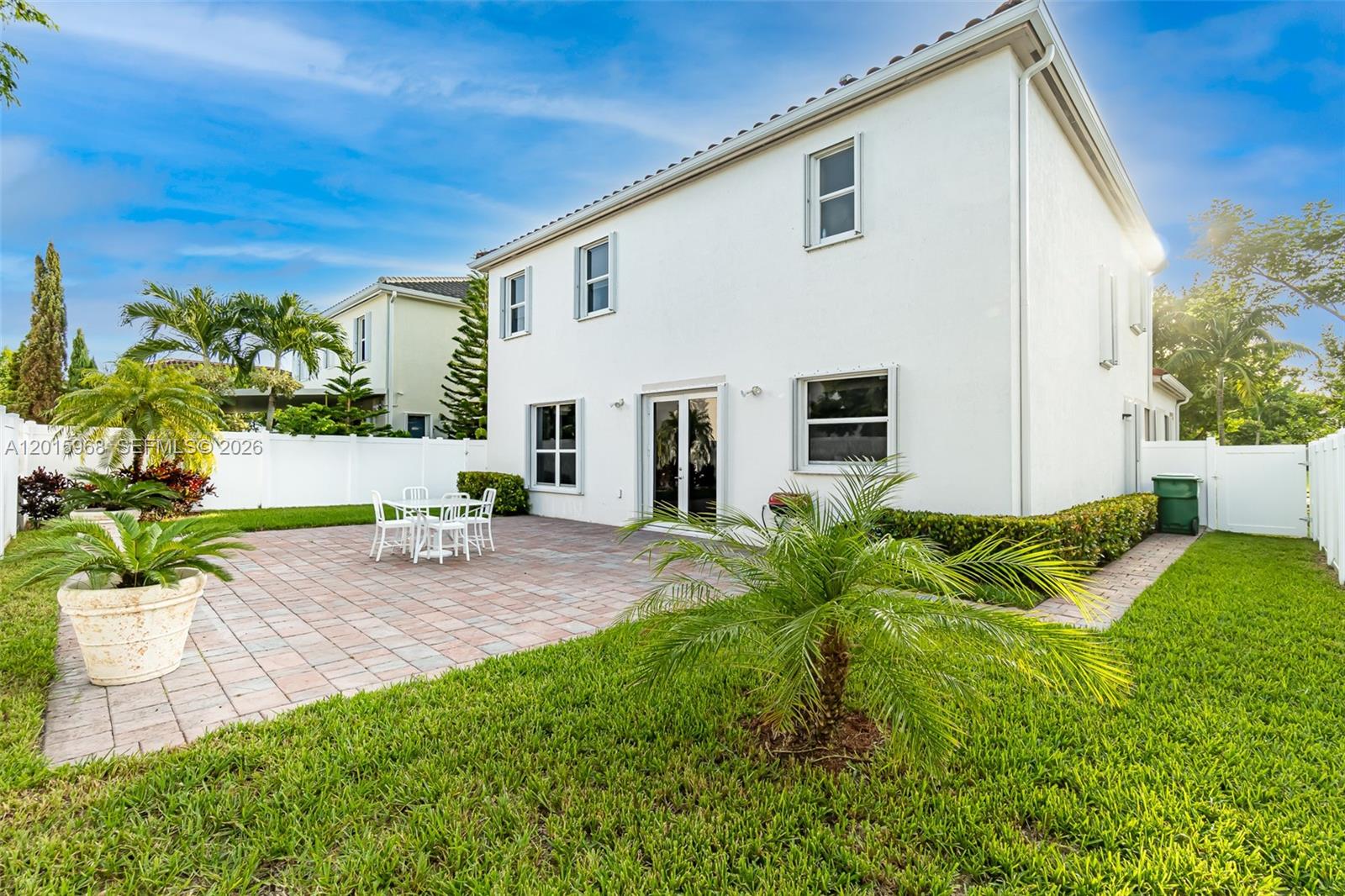 The exterior of a two-story white house features a paved patio and a grassy yard — 17046 SW 94th Ln, Miami FL 33196, MIAMI, FL