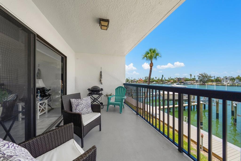 A balcony with wicker chairs, a grill, and a view of a canal and boat docks — 3111 PASS A GRILLE WAY UNIT 110, ST PETERSBURG, FL