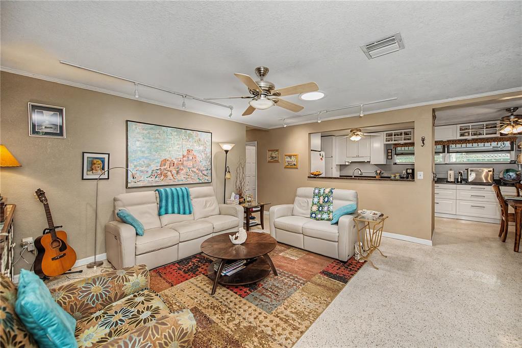 A living room with two beige sofas, a patterned rug, and an open kitchen pass-through — 3017 CHICORY TERRACE, PUNTA GORDA, FL