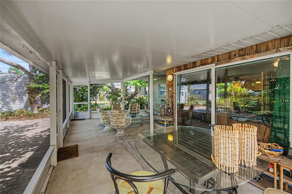 A screened-in patio features a concrete floor, glass-topped dining table, and wicker seating area — 3017 CHICORY TERRACE, PUNTA GORDA, FL