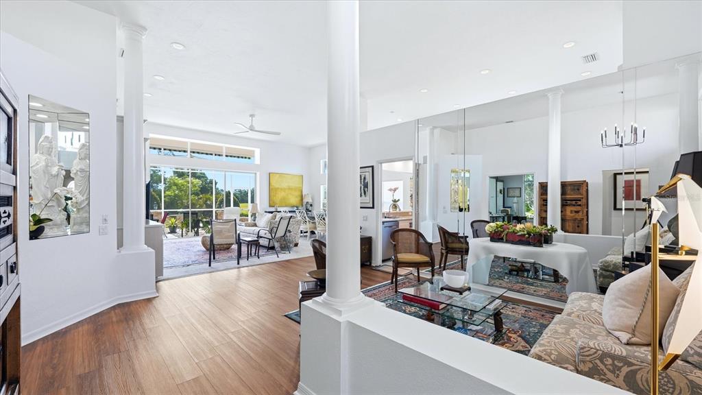 A bright, open-concept living area features white columns, hardwood floors, and large glass sliding doors — 8009 HAMPTON COURT, UNIVERSITY PARK, FL