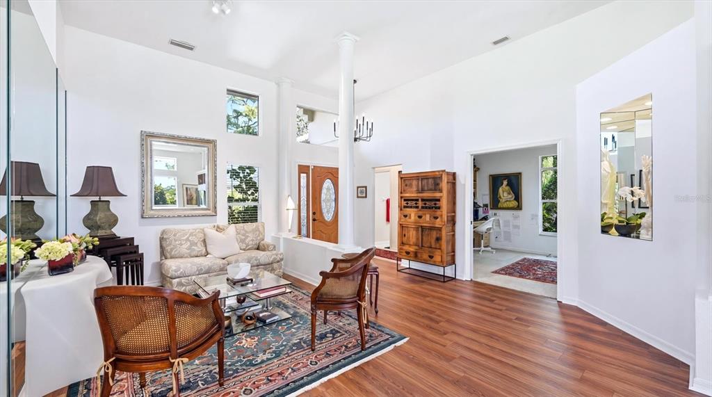 A living room with high ceilings, wood floors, a patterned rug, and a central column — 8009 HAMPTON COURT, UNIVERSITY PARK, FL