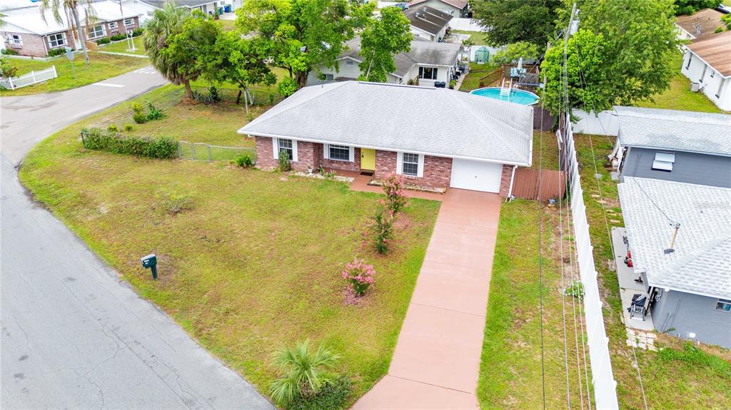 An aerial view of a single-story brick house with a white roof and driveway — 5435 TANGERINE DRIVE, ZEPHYRHILLS, FL