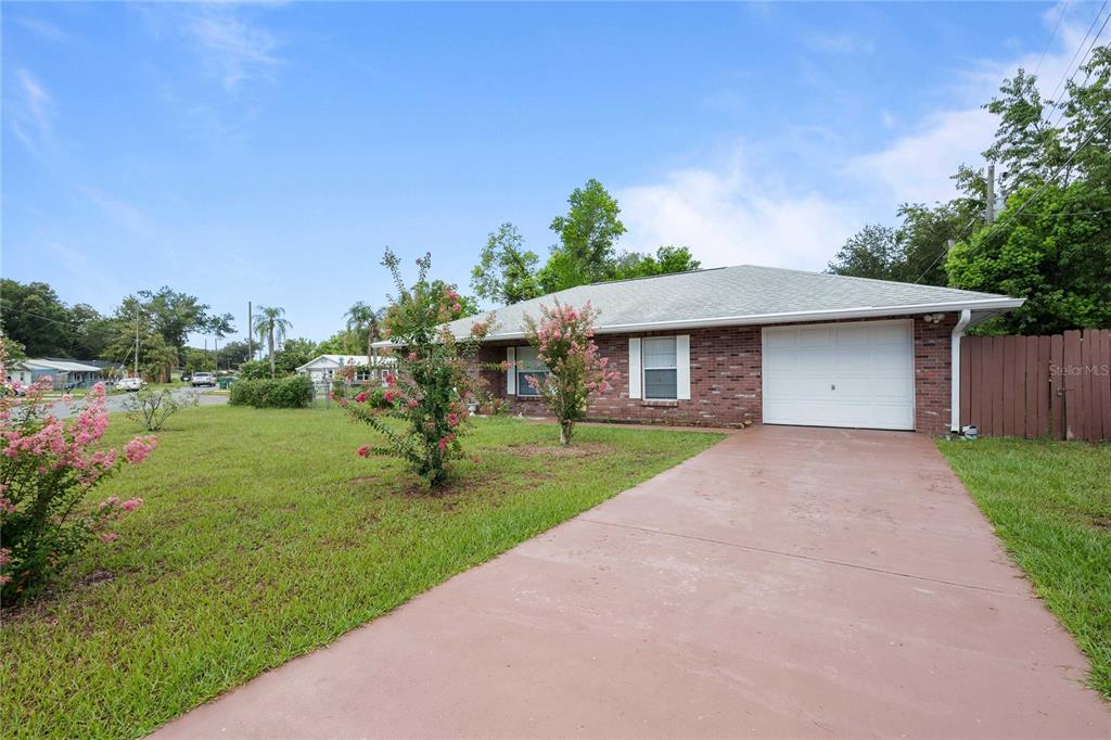 A single-story brick house with a white garage door and a concrete driveway — 5435 TANGERINE DRIVE, ZEPHYRHILLS, FL