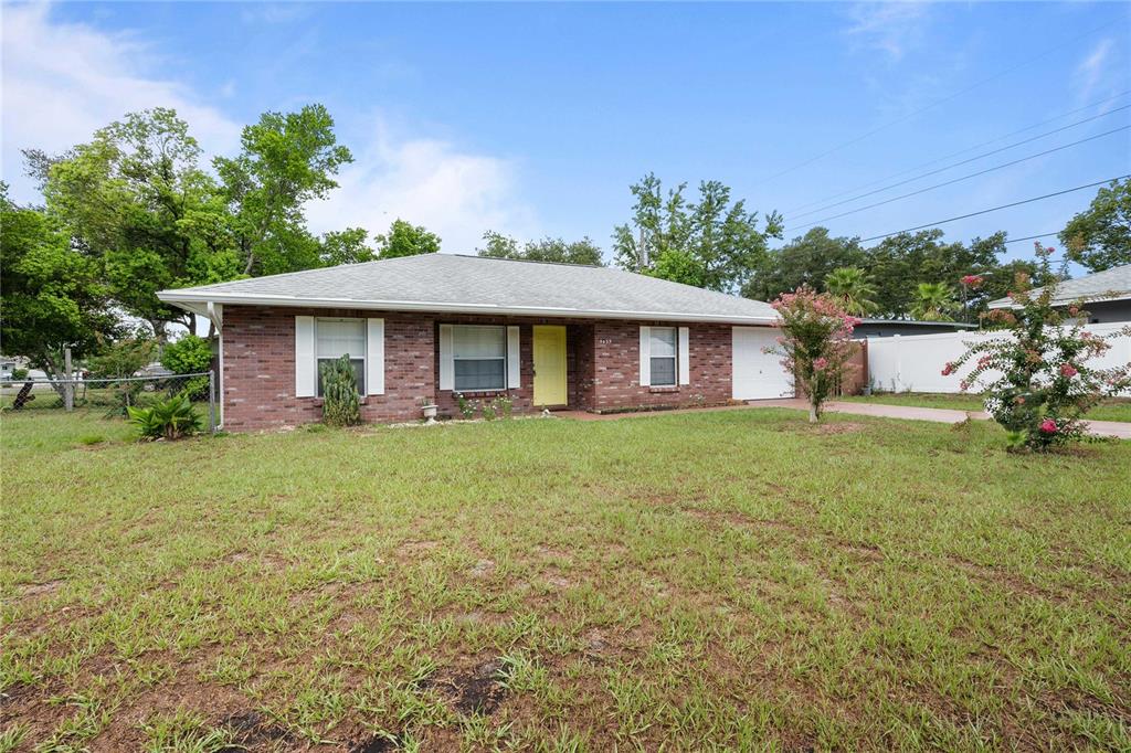 A single-story brick house with a yellow front door and an attached garage — 5435 TANGERINE DRIVE, ZEPHYRHILLS, FL