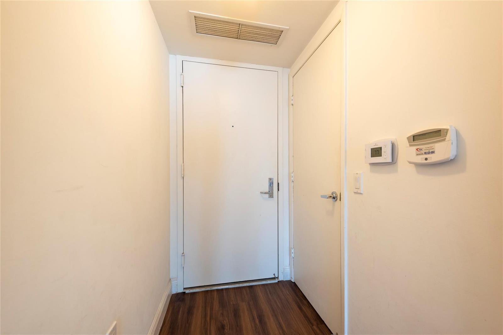 A hallway features wood-look flooring, two white doors, and wall-mounted climate control panels — 41 SE 5th Street # 1315, Miami FL 33131, MIAMI, FL