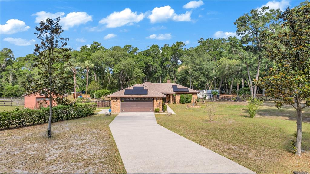 A single-story brick house with a concrete driveway, solar panels, and a detached garage — 721 MCGREGOR ROAD, DELAND, FL