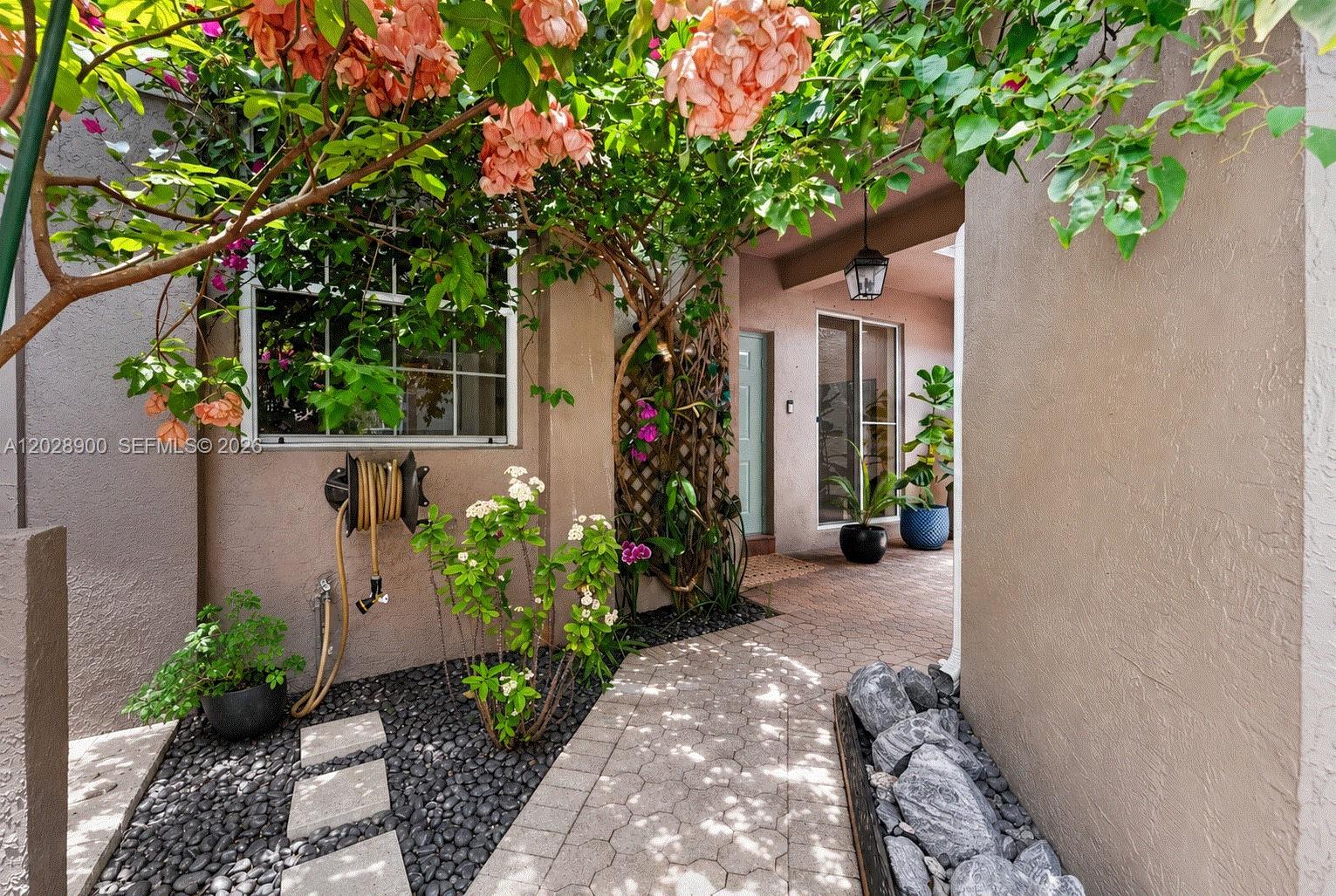 A paved walkway leads to a home entrance framed by lush flowering vines and landscaping — 2411 Aragon Blvd # 2, Sunrise FL 33322, SUNRISE, FL