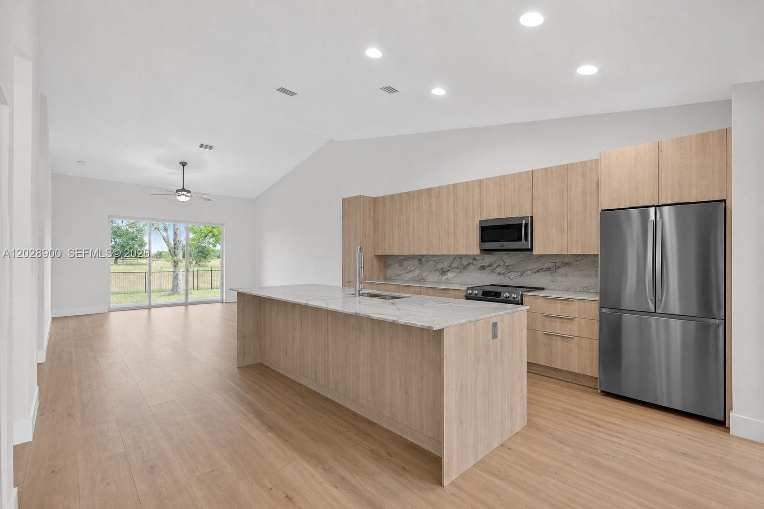 A modern kitchen features light wood cabinets, a marble island, and stainless steel appliances — 2411 Aragon Blvd # 2, Sunrise FL 33322, SUNRISE, FL