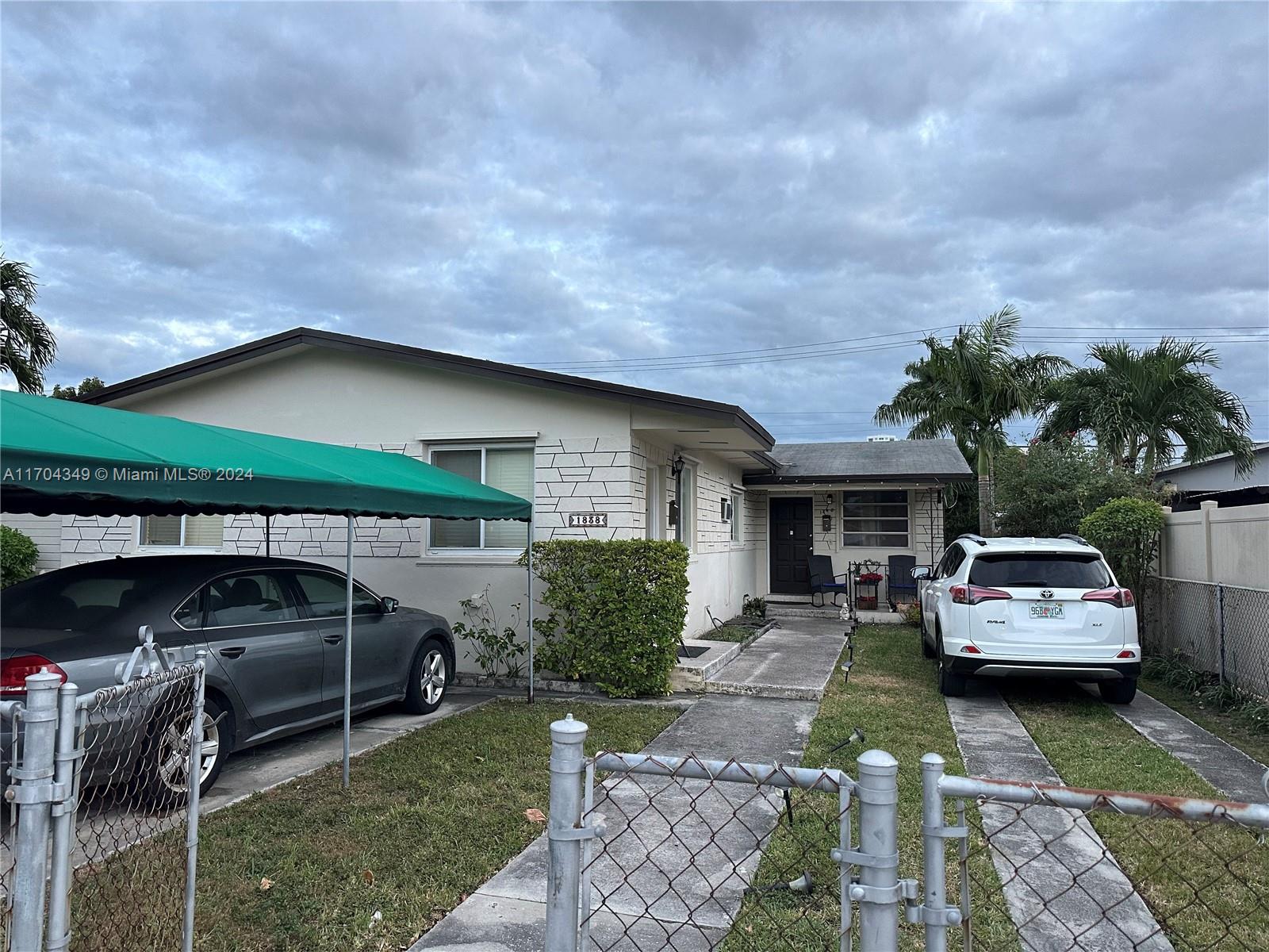 A single-story house with a green carport, two parked cars, and a chain-link fence — 1838 NW 18th St, Miami FL 33125, MIAMI, FL