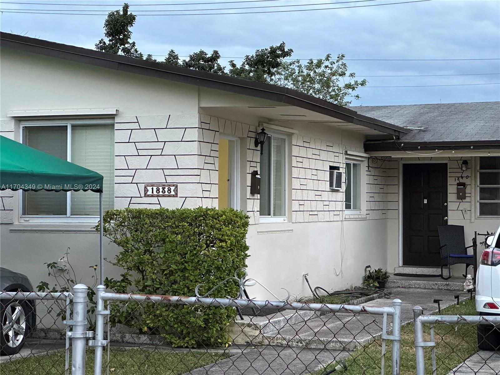 The exterior of a single-story house features a white facade with decorative stone-patterned accents — 1838 NW 18th St, Miami FL 33125, MIAMI, FL