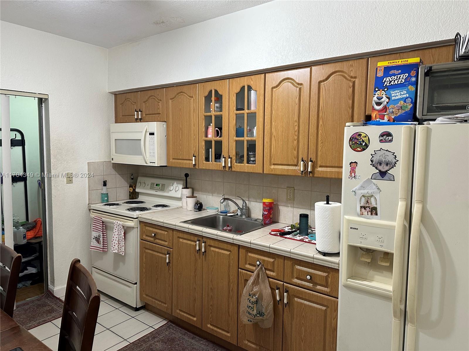 A kitchen features wood cabinets, white appliances, a tiled countertop, and a tiled floor — 1838 NW 18th St, Miami FL 33125, MIAMI, FL