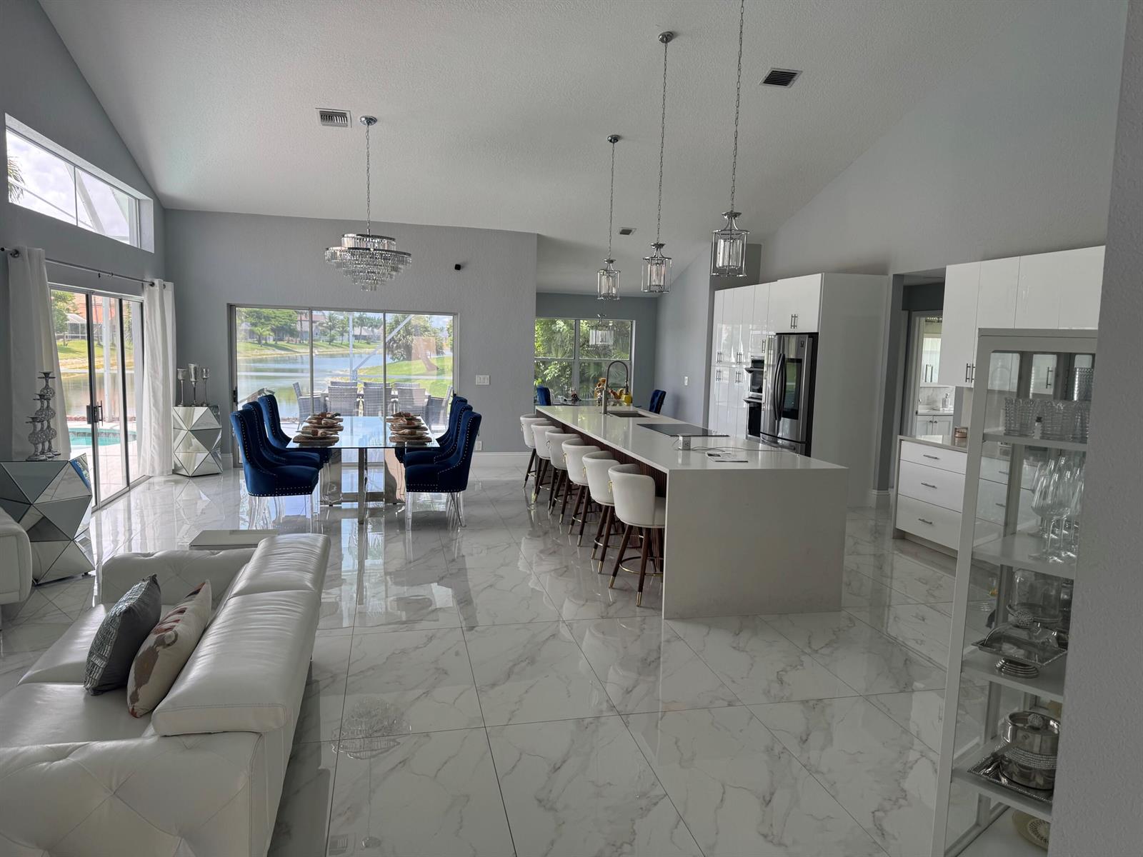 An open-concept living area features a white kitchen island, dining table, and marble tile floors — 22257 Collington Drive, Boca Raton FL 33428, BOCA RATON, FL