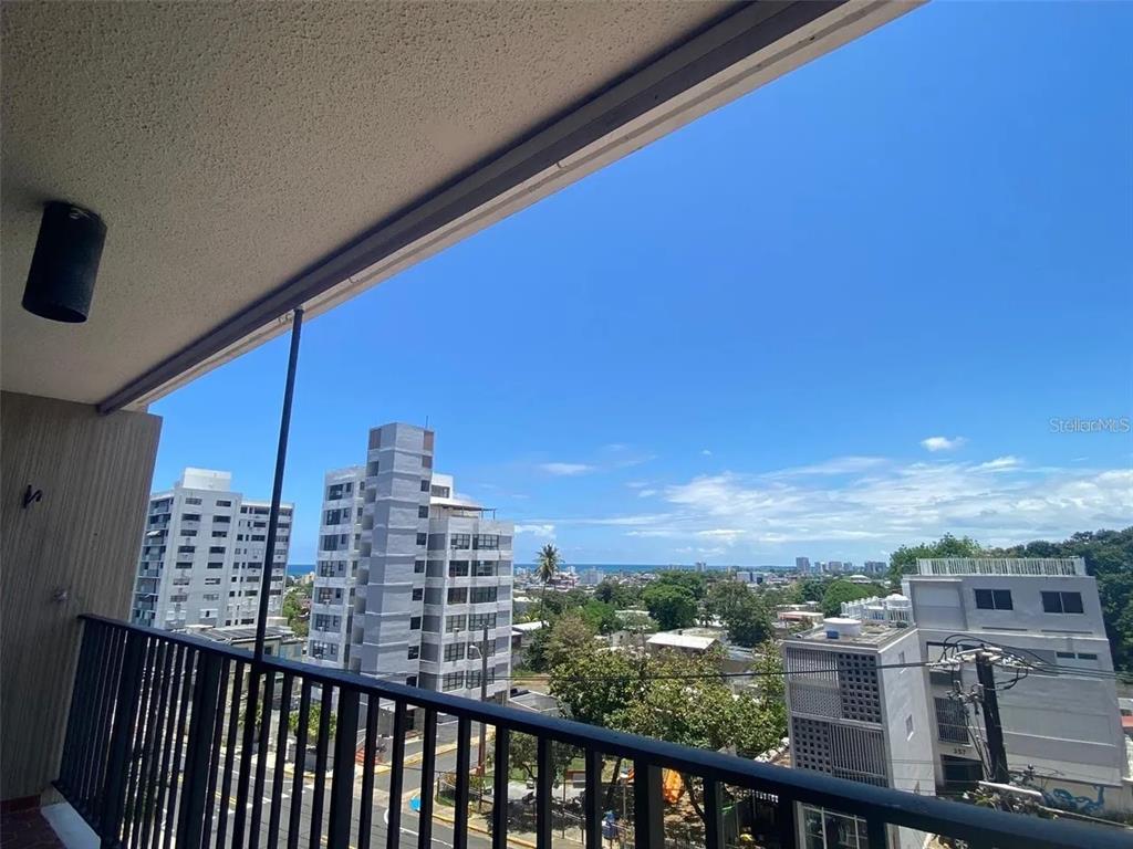 A balcony with a black metal railing overlooks a city skyline and the ocean — 364 CALLE SAN JORGE UNIT 3G, SAN JUAN, PR