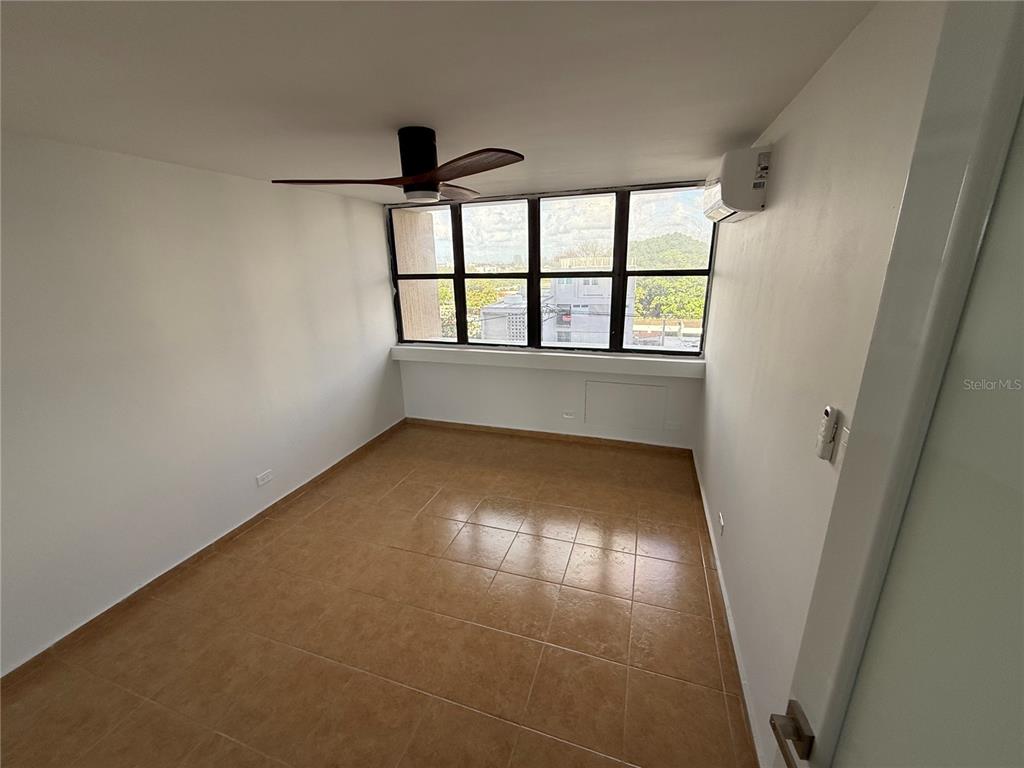 An empty room features tan tile flooring, a ceiling fan, and a large window wall — 364 CALLE SAN JORGE UNIT 3G, SAN JUAN, PR