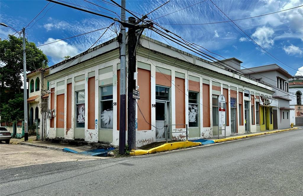 A corner view of a weathered, single-story commercial building with orange and white exterior walls — 58 MUÑOZ RIVERA ESQ CORCHADO, JUNCOS, PR