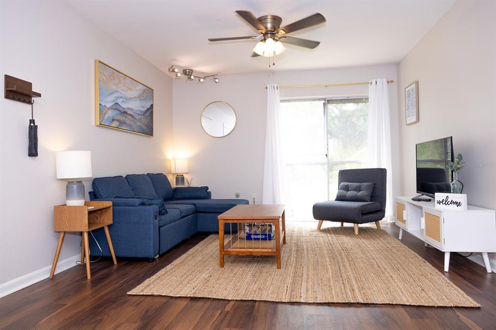 A living room features a blue sectional sofa, a coffee table, and a grey armchair — 1700 SW 16TH COURT UNIT C5, GAINESVILLE, FL