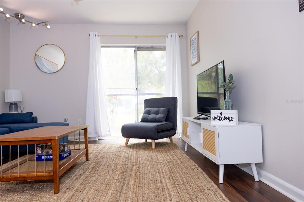 A living room features a blue sofa, a gray accent chair, and a white media console — 1700 SW 16TH COURT UNIT C5, GAINESVILLE, FL