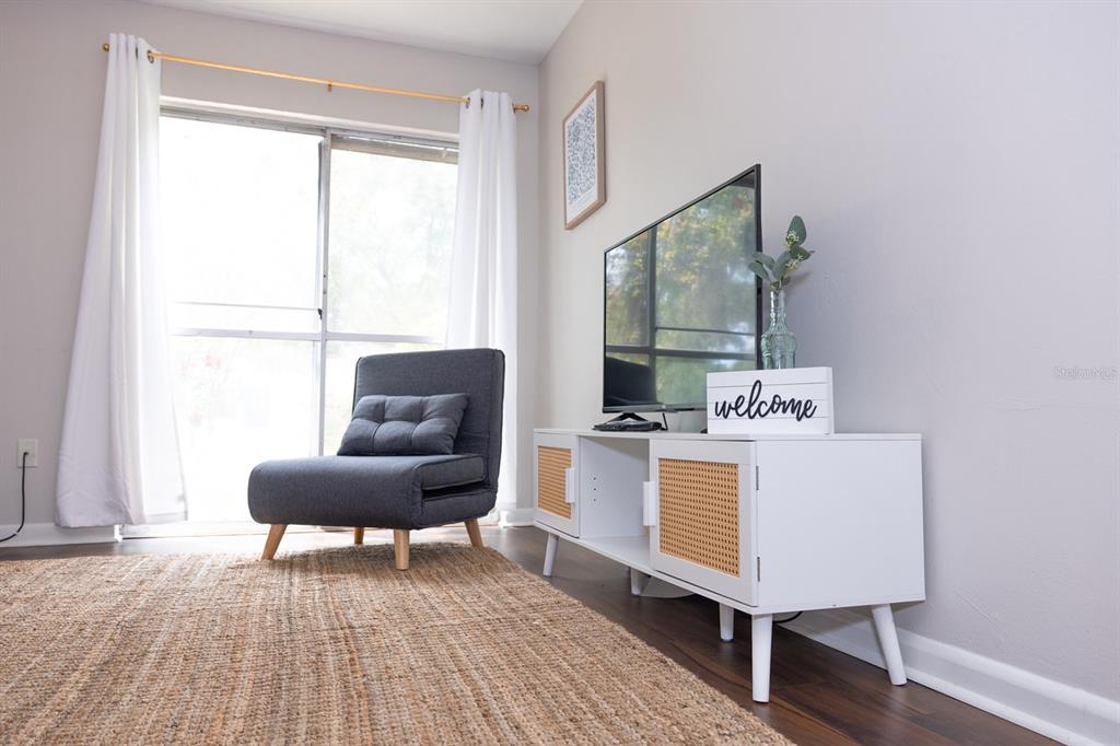 A living room features a gray chair, a white media console, and a jute rug — 1700 SW 16TH COURT UNIT C5, GAINESVILLE, FL