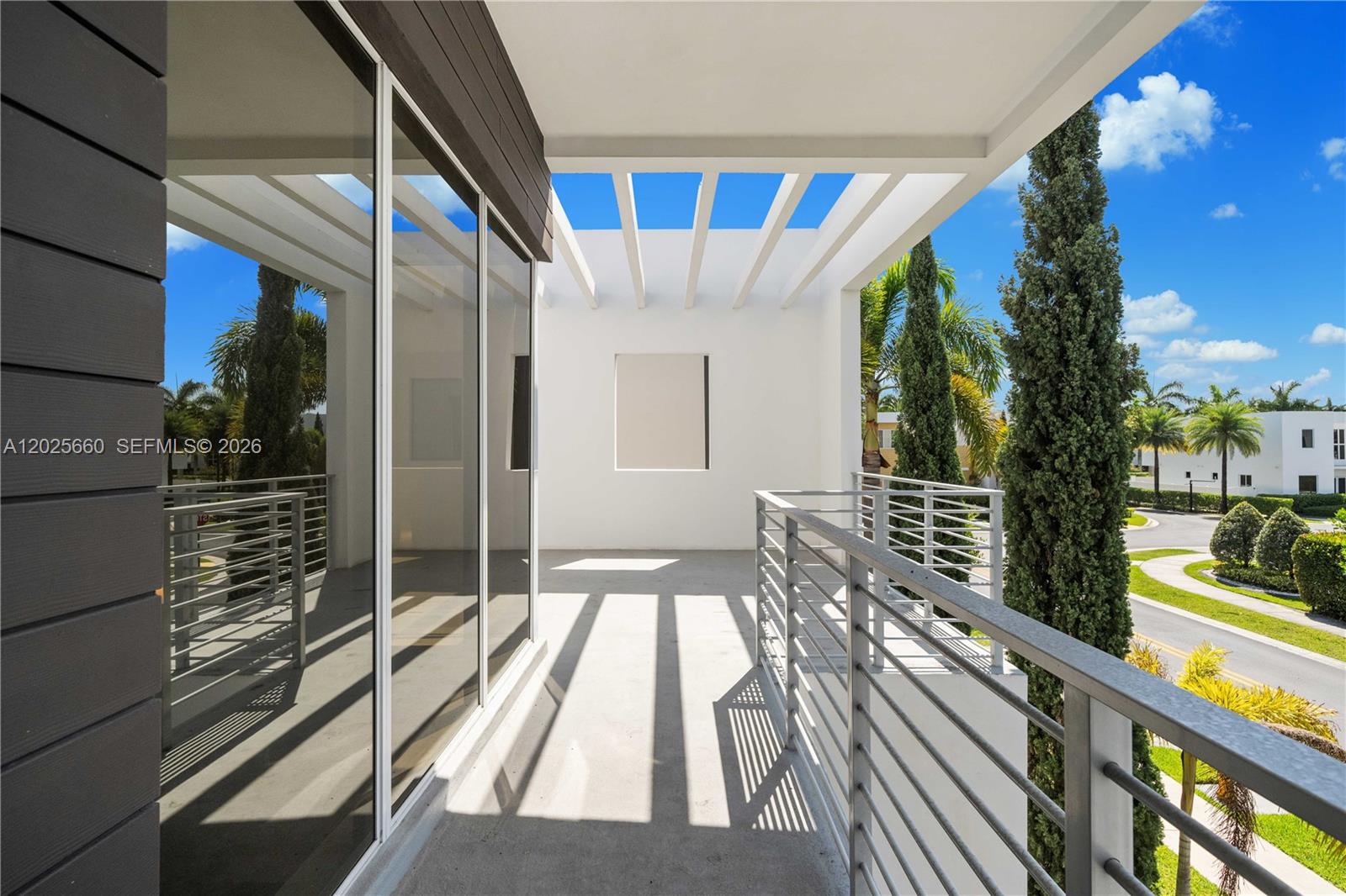 A modern balcony features a metal railing, glass sliding doors, and an open-slatted roof — 9915 NW 75th St, Doral FL 33178, DORAL, FL