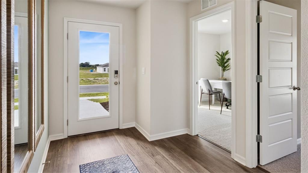 A modern kitchen features white cabinets, stainless steel appliances, and a central island with seating — 1081 PORTLAND STREET, DELTONA, FL