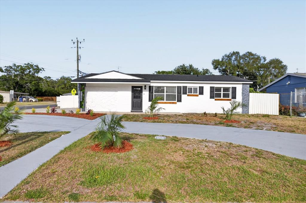 A white, single-story house with a dark roof, black shutters, and a paved driveway — 13589 120TH STREET, LARGO, FL