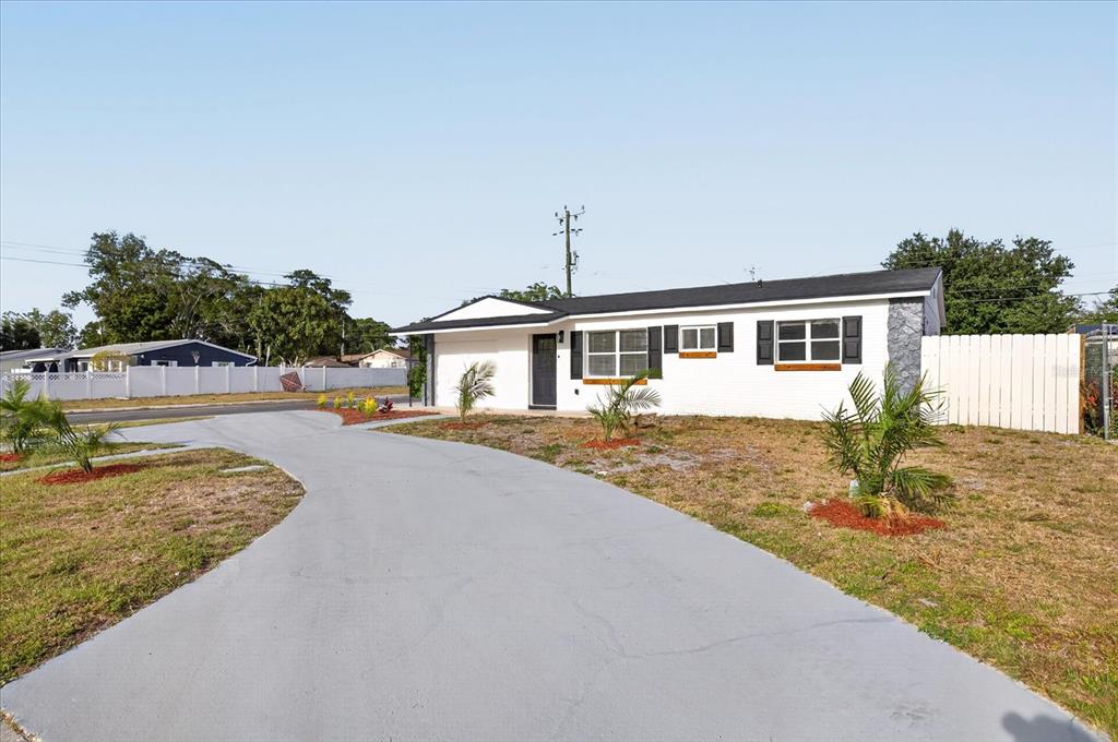 A white single-story house with a black roof and a curved gray concrete driveway — 13589 120TH STREET, LARGO, FL