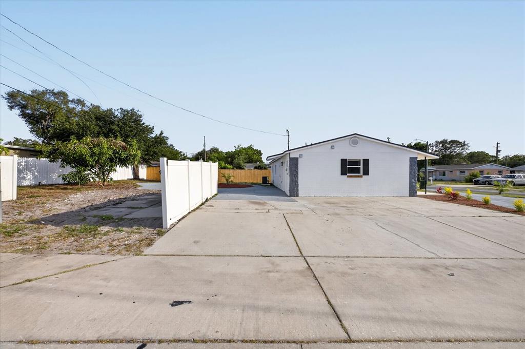 A white, single-story house features a large concrete driveway and a white vinyl fence — 13589 120TH STREET, LARGO, FL