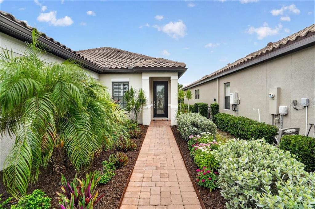 A brick walkway leads to the front entrance of a house with a tile roof — 4642 CRESTPOINT WAY, PALMETTO, FL