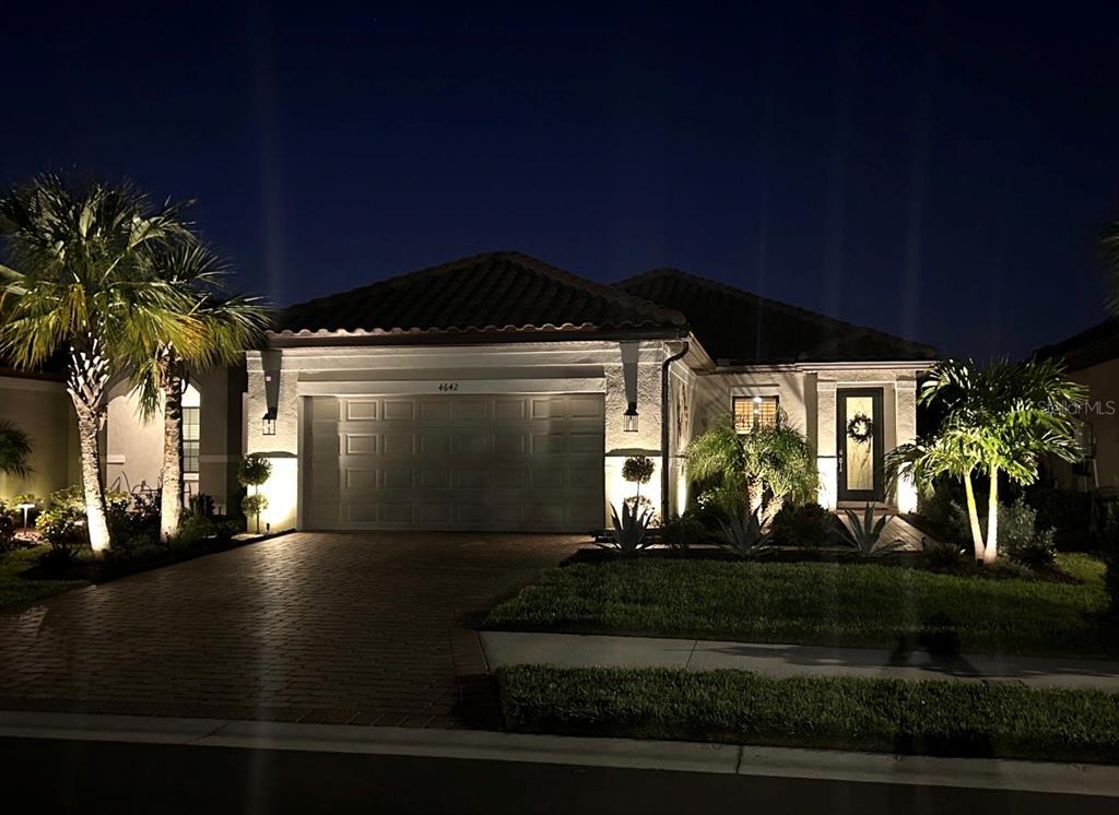 A single-story house with a paved driveway and landscape lighting at night — 4642 CRESTPOINT WAY, PALMETTO, FL