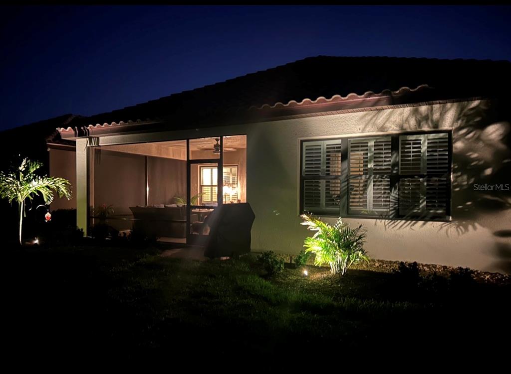 The exterior of a house at night featuring a screened-in patio and landscape lighting — 4642 CRESTPOINT WAY, PALMETTO, FL