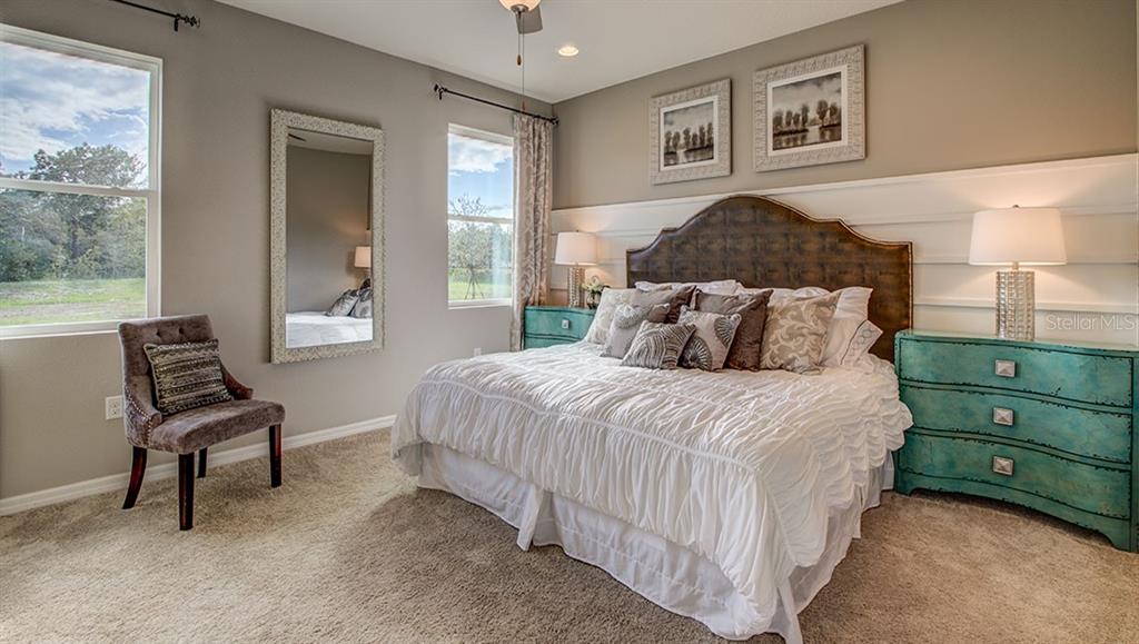 A bedroom features a bed with a dark headboard, white bedding, and two teal nightstands — 7325 SW 45TH COURT, OCALA, FL