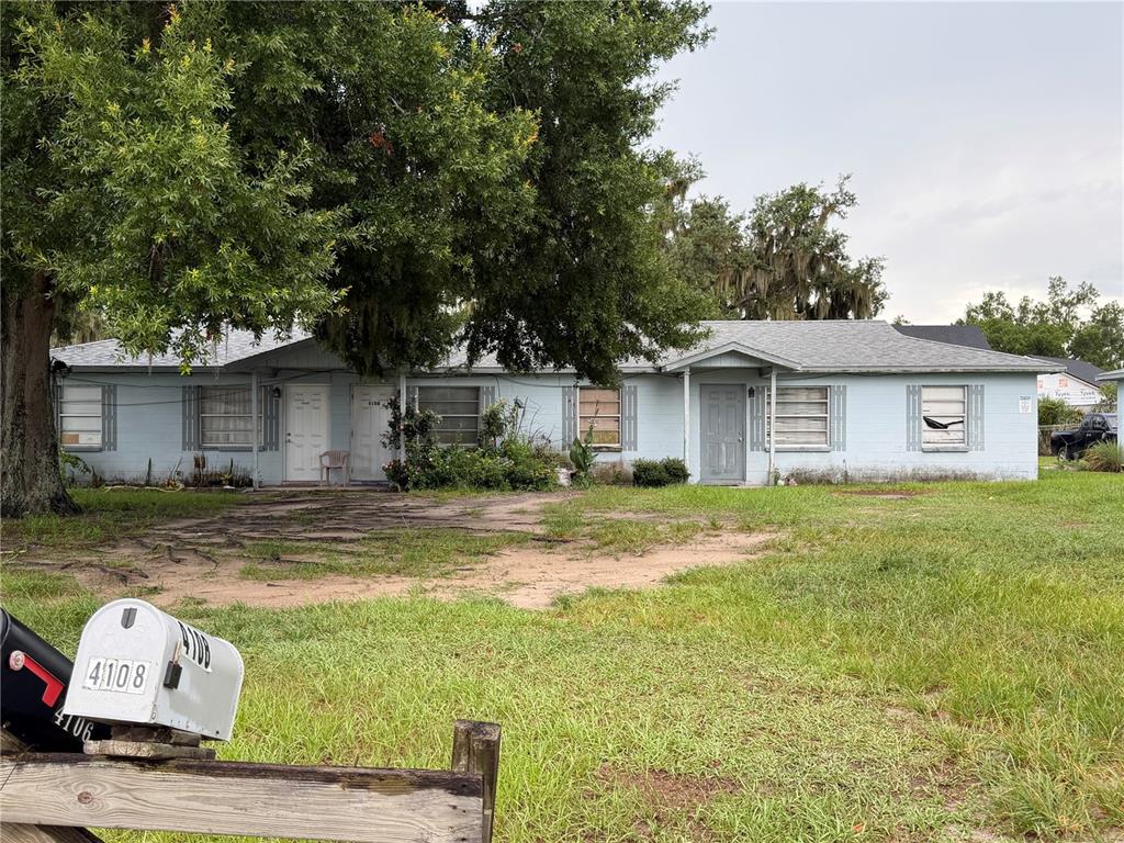 A single-story light blue house with multiple entrances sits behind a large tree and lawn — 4106 WILLOW SOUTH DRIVE, MULBERRY, FL